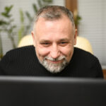 Mature man looking through his laptop online angol tanulas